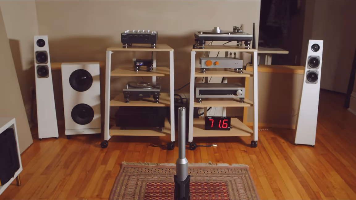 Listening room with two equipment racks between white speakers and a measurement microphone in front