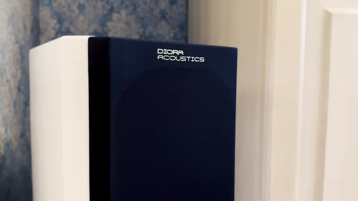 The Diora Acoustics Chors 5's gloss-white cabinet wearing its black magnetic fabric grille with the Diora Acoustics logo