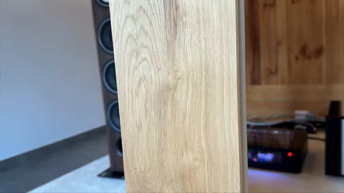 A Woody Queen panel standing in the listening room beside a floor-standing speaker and the audio rack