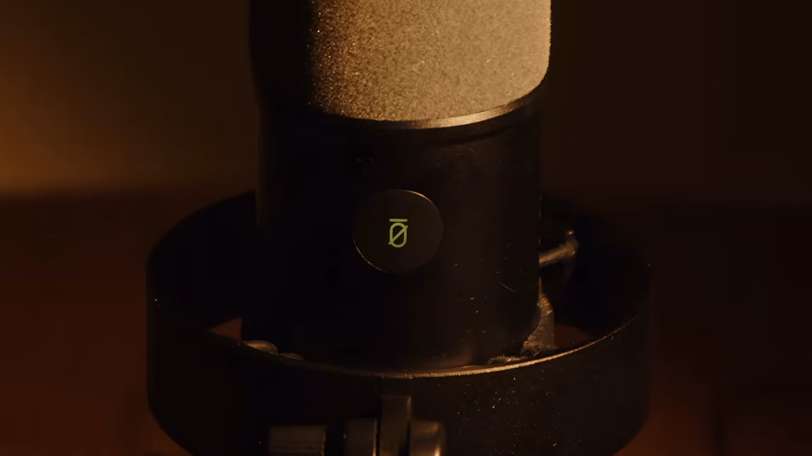 Close-up of the K688's tap-to-mute pad on the front of the body, its crossed-circle symbol backlit green to show the microphone is live