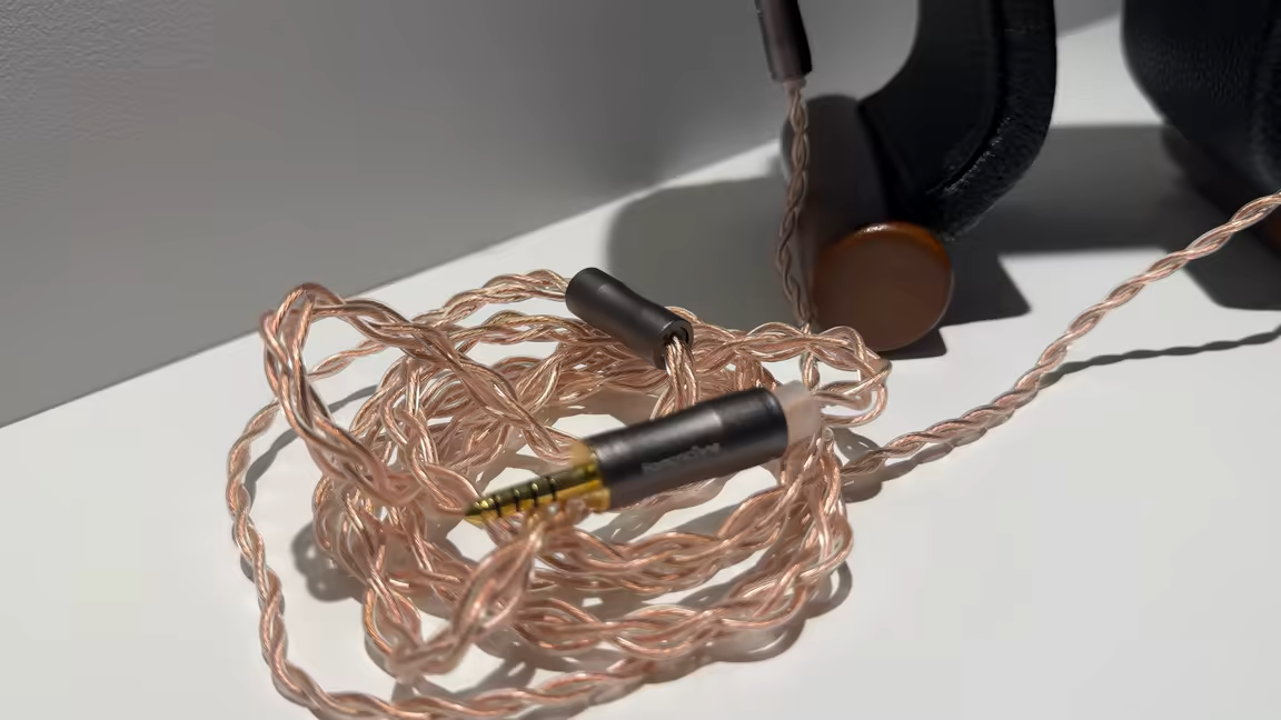 The HarmonicDyne Eris's thick copper braided cable terminating in a 4.4mm balanced plug, beside the headphone