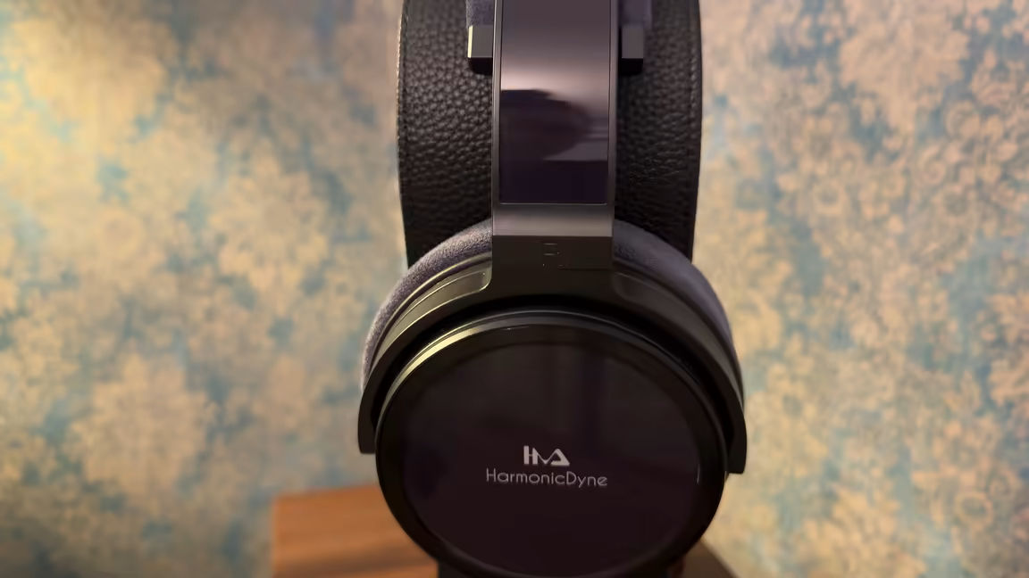 The HarmonicDyne Eris on its stand, showing the glossy black earcup with the HarmonicDyne logo and suede headband