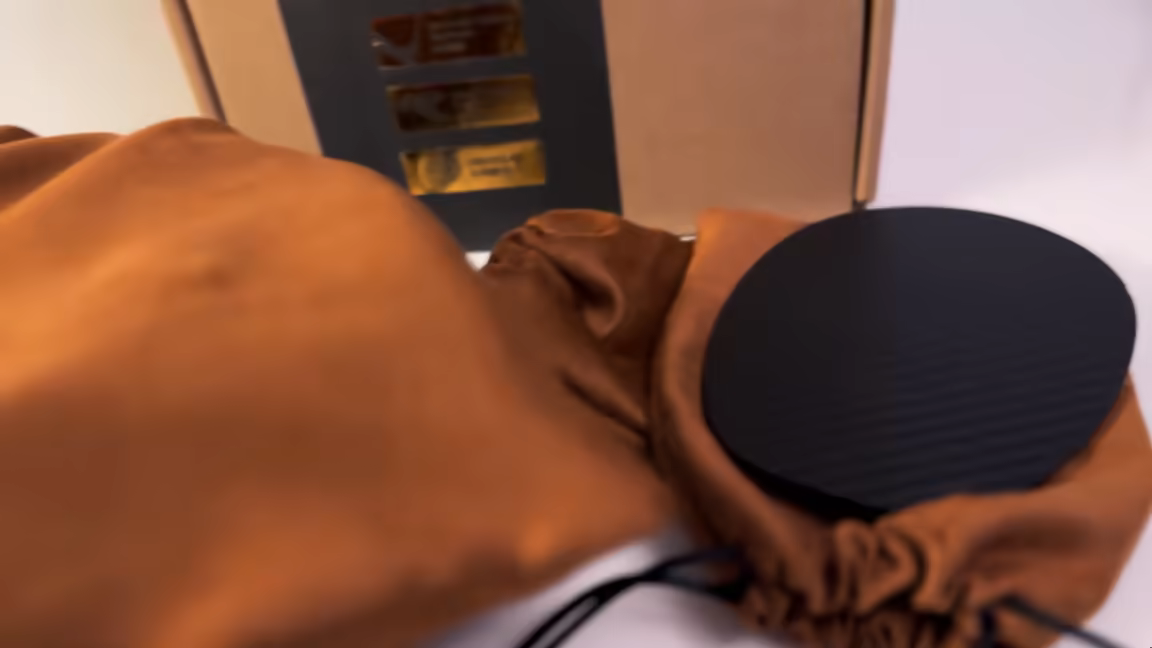 One of the Arya Unveiled's carbon-textured Magnetic Veils on its suede pouch beside the box