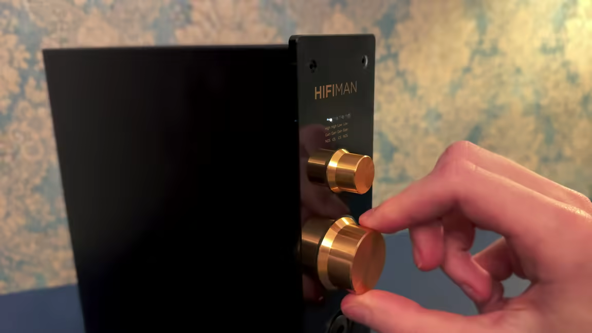 A hand turning the EF499's golden gain knob, which selects between High/Low gain and NOS/OS oversampling modes