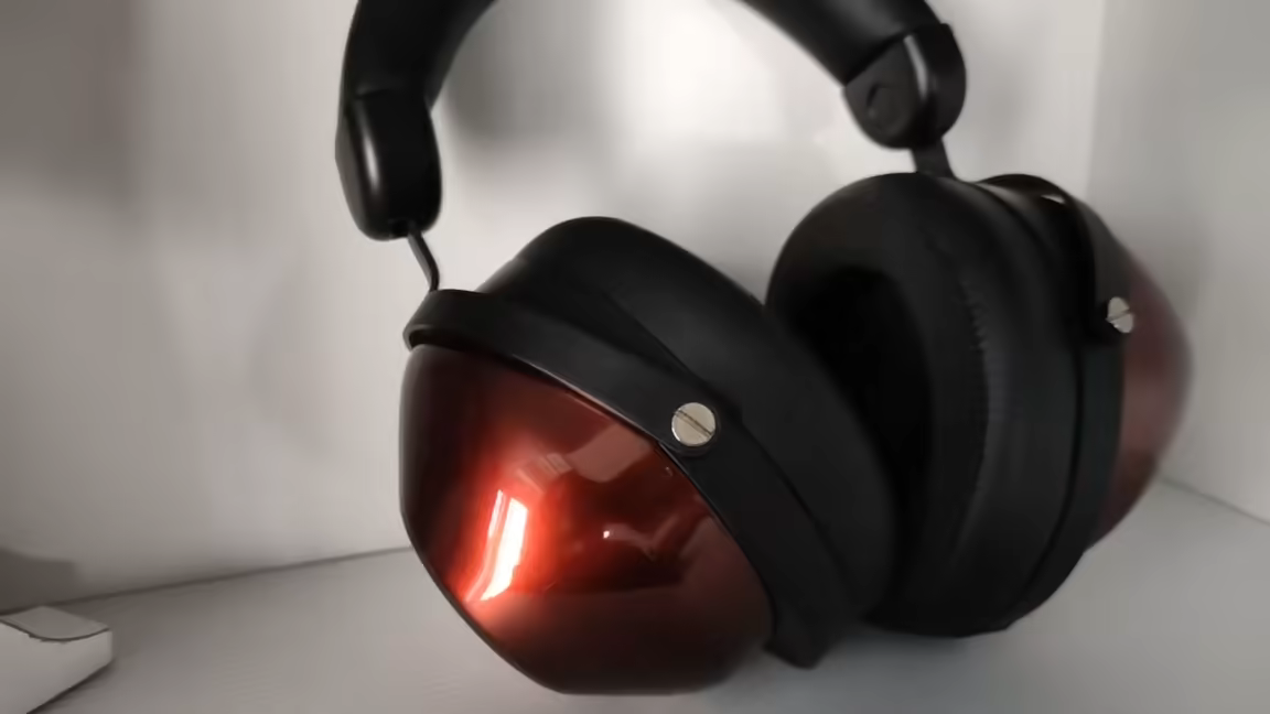 The full HIFIMAN HE-R9 headphone at a three-quarter angle, showing both large glossy red closed-back cups, the black pads, and the solid black headband and gimbals