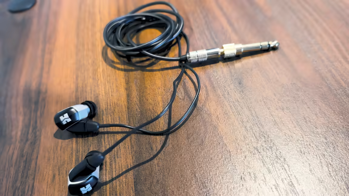 The HIFIMAN RE2000 PRO Silver's CNC aluminium shells, detachable cable, and gold-plated plug on a wooden desk