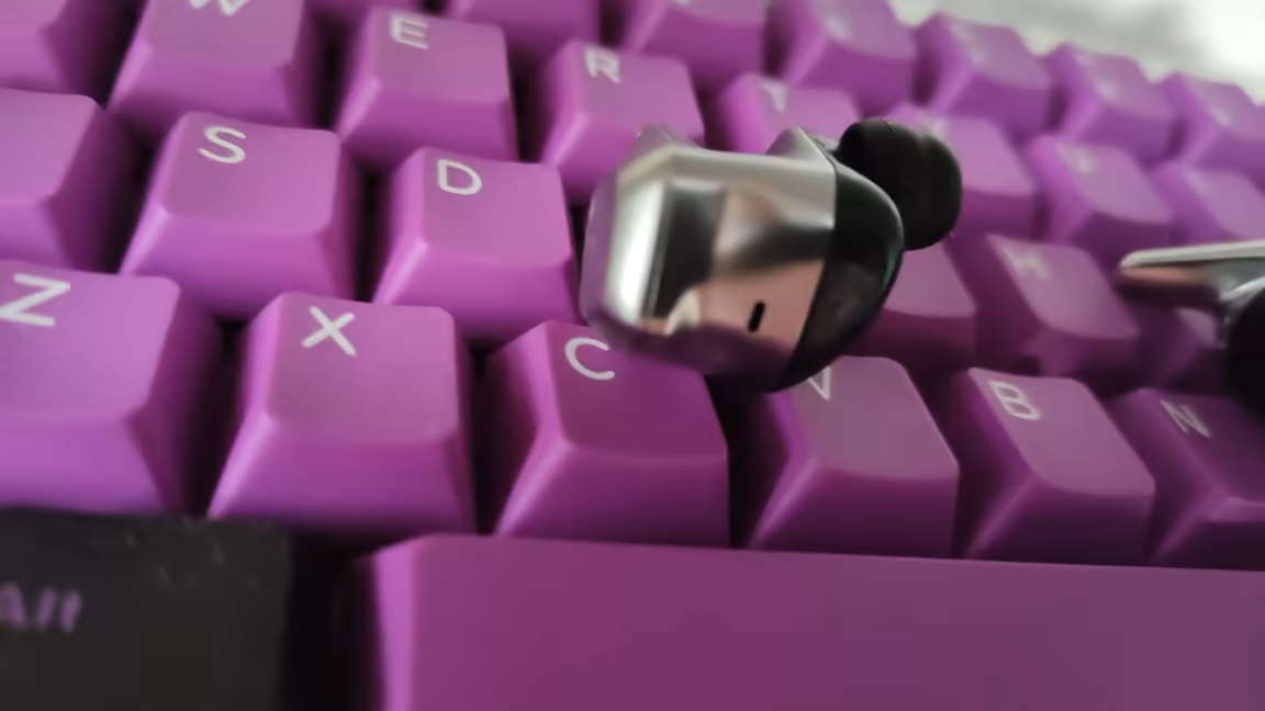 Close-up of a HIFIMAN Svanar Wireless earbud showing its chromed swan-shaped nozzle, silver-and-black body, and silicone ear tip