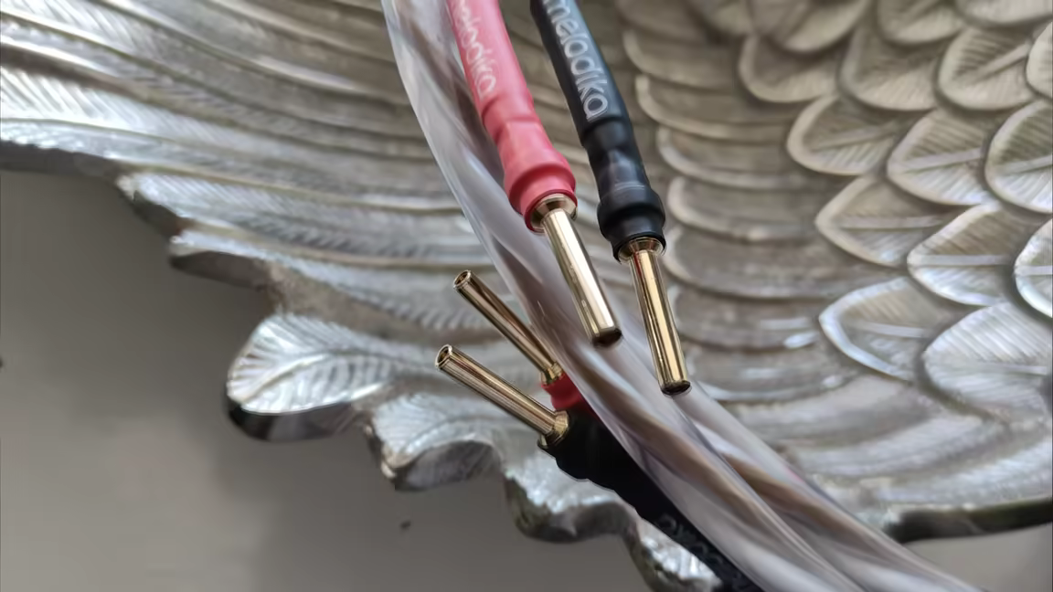 The cable's gold banana plugs with red and black Melodika boots terminating the brown-and-white wires