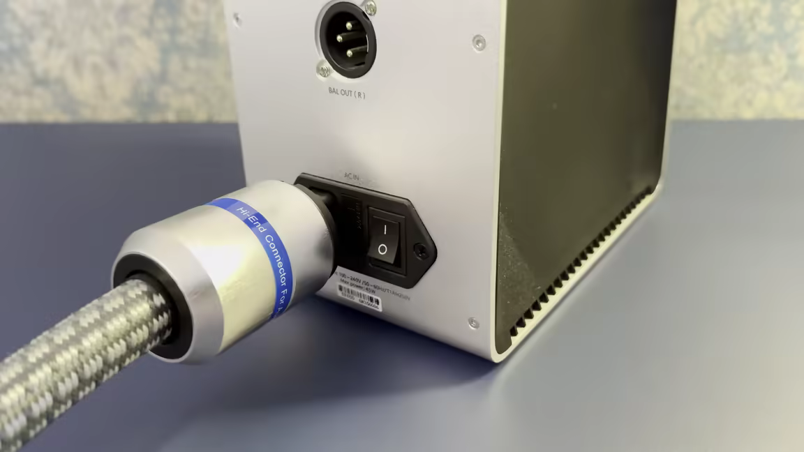The P902E6R's big aluminium-alloy IEC plug with its blue Hi-End Connector sticker, plugged into an amplifier's mains inlet