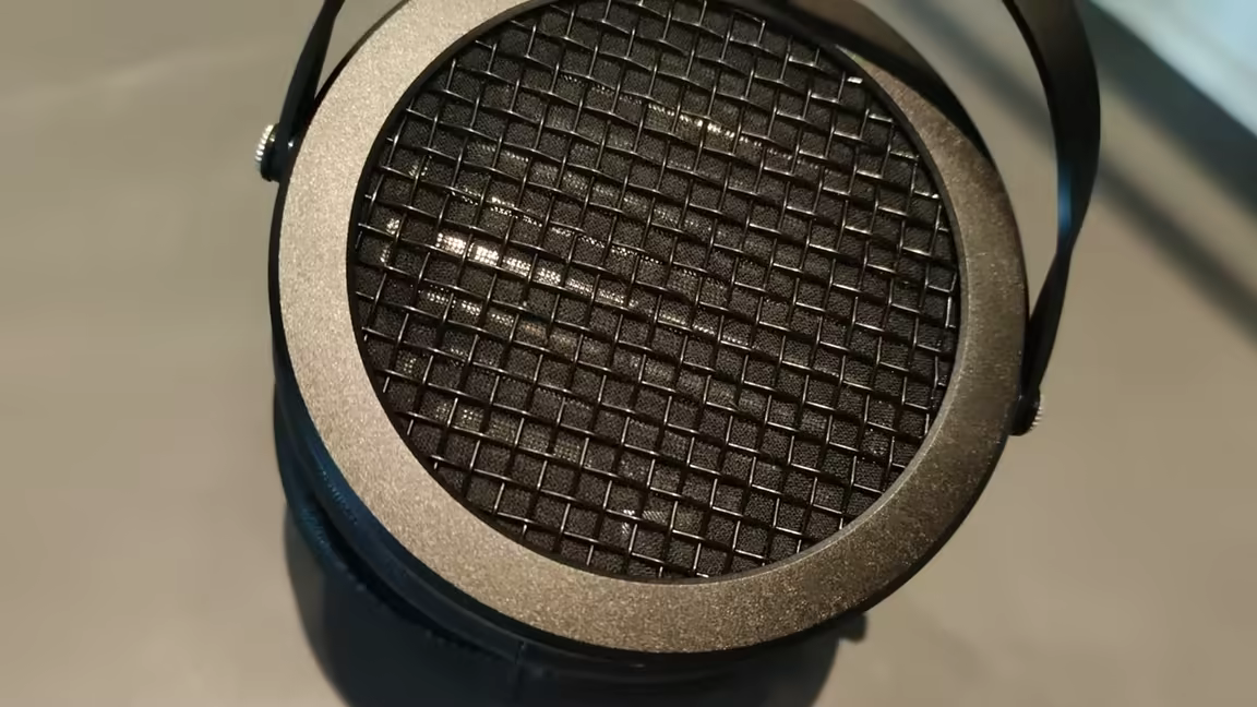 The HIFIMAN Sundara's open-back ear cup, showing the metal grille, matte cast frame, and headband bar