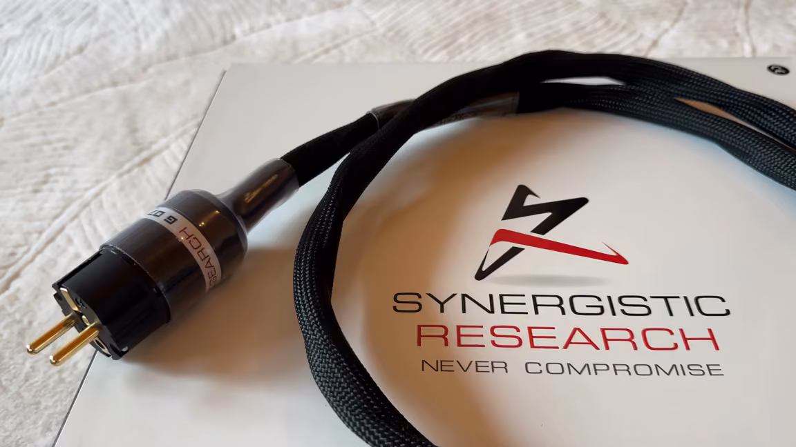 The bundled Synergistic Research Foundation power cable coiled on the gloss white box, its black braided sleeve leading to a gold-pinned Schuko plug