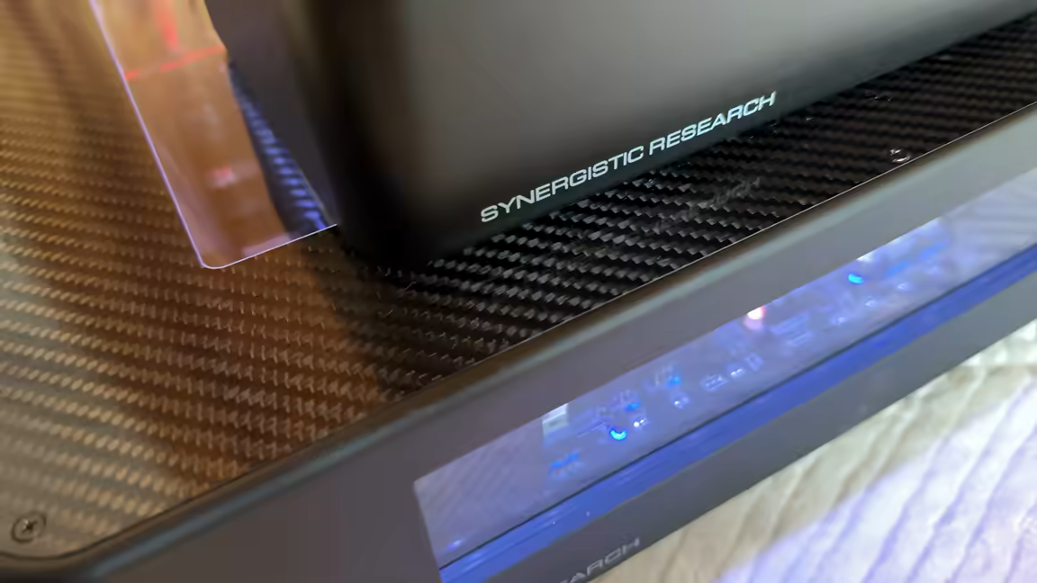 The carbon-topped router stacked on the PowerCell 14, whose blue-lit internals glow through the plexiglass window beneath it