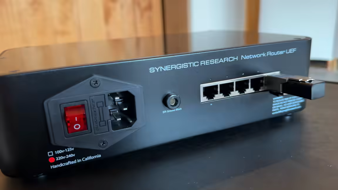 Close view of the rear panel: red rocker switch, fused IEC power inlet, an SR Ground Block jack, and five ethernet ports with one cable plugged in