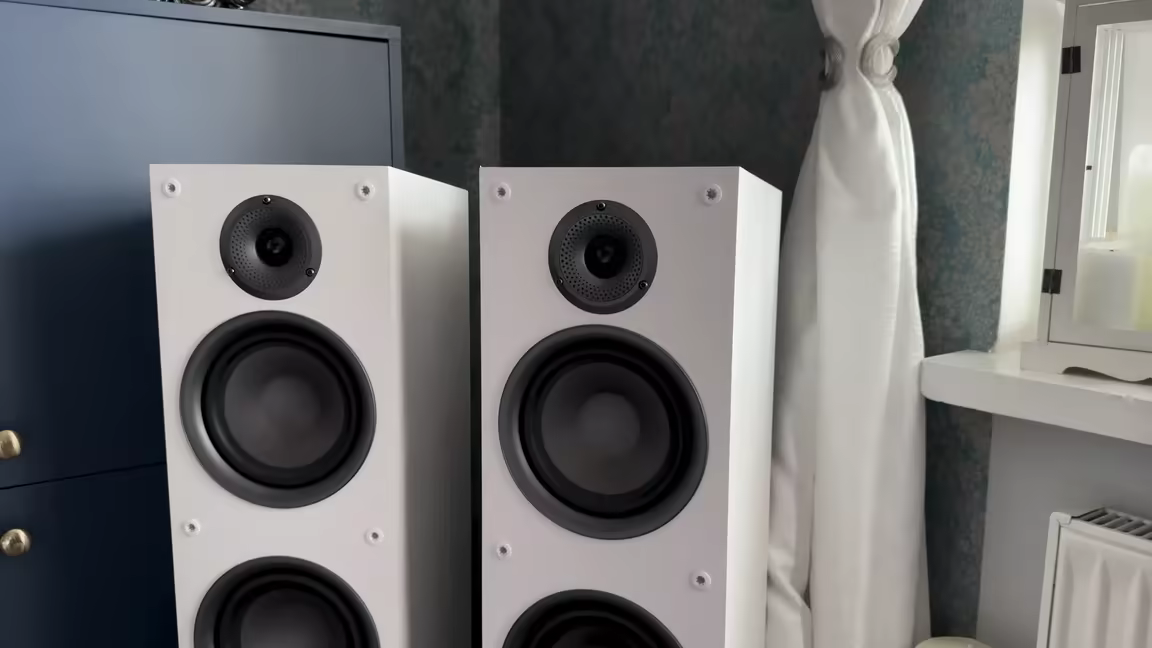 The pair of Taga TAV-607F floor-standers with grilles off, showing the three-way layout: tweeter, midrange driver, and 6.5-inch woofer